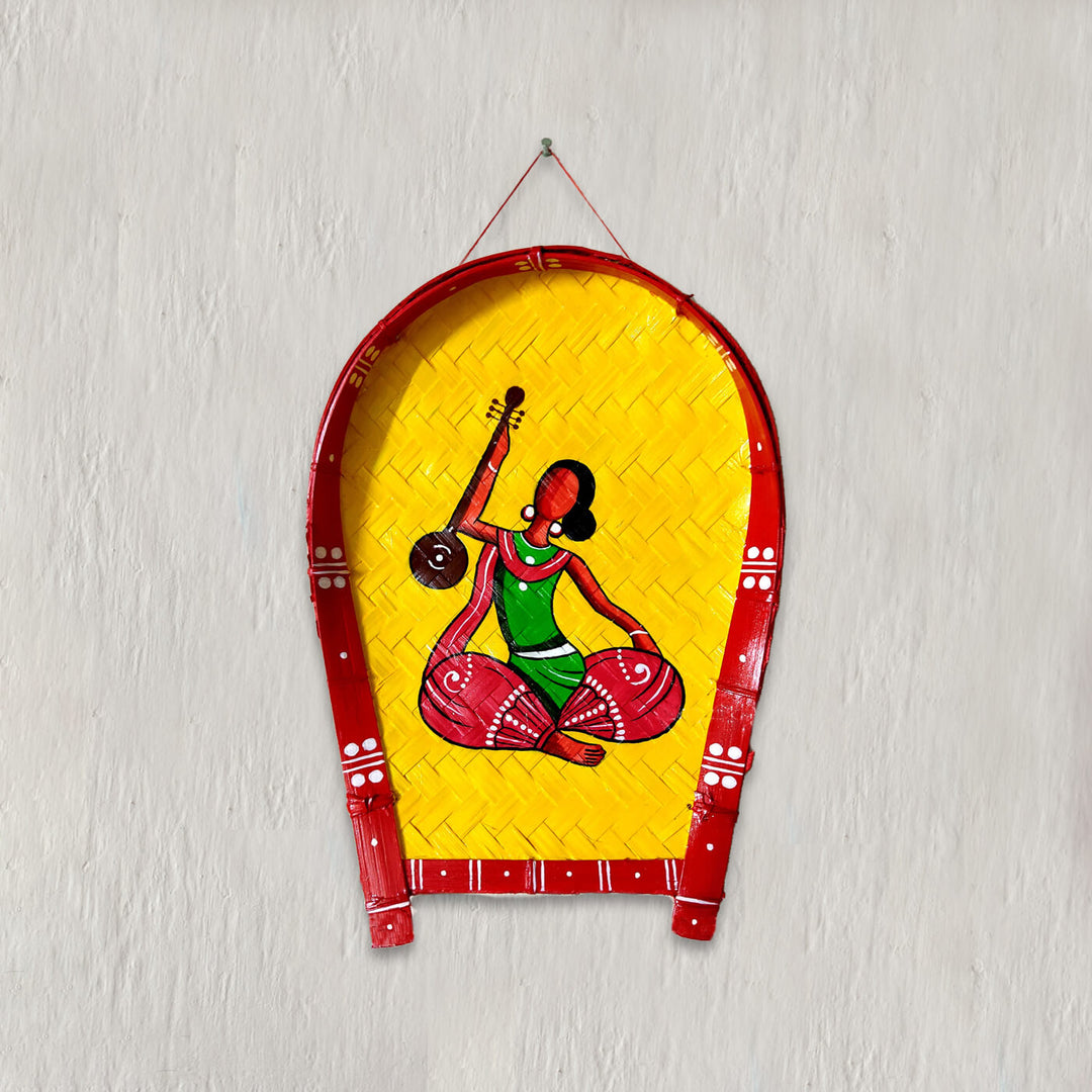 Handpainted bamboo wall decor featuring a woman in a red and green saree playing a musical instrument.