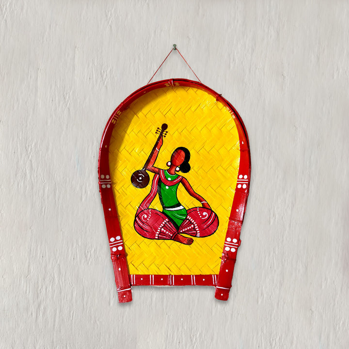 Handpainted bamboo wall decor featuring a woman in a red and green saree playing a musical instrument.