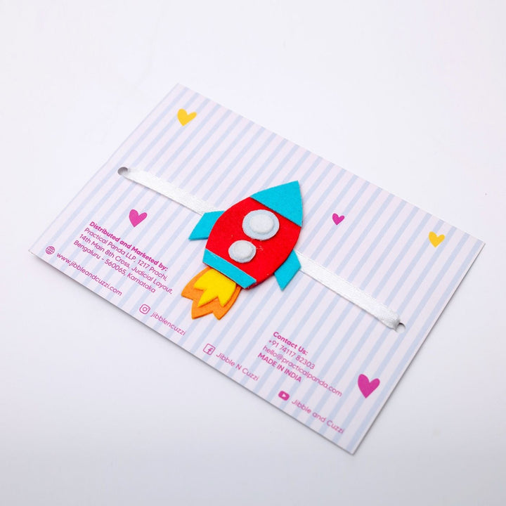 Handmade Space Whiz Rocket Felt Kids Rakhi - Angled View Showing Packaging and Ribbon