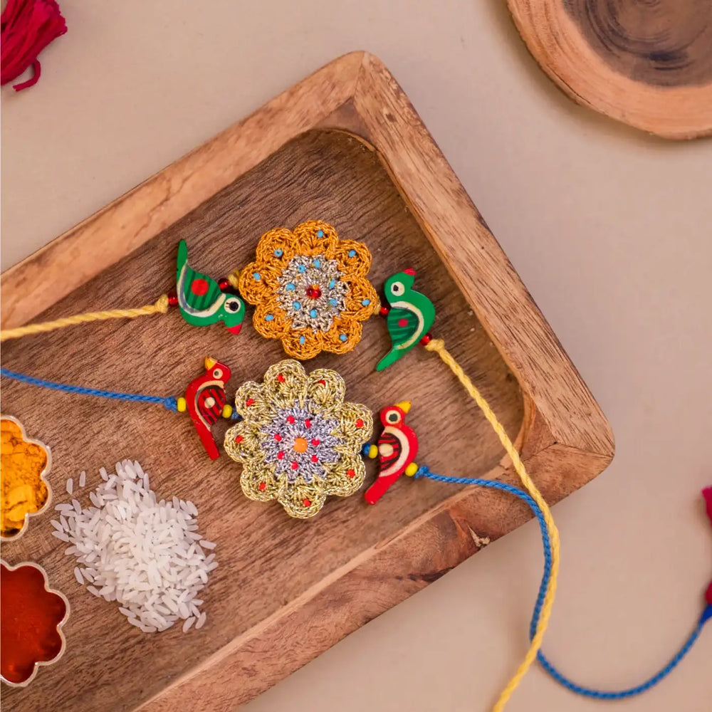 Handmade Crochet Flower And Birds Rakhi With Roli Chawal Set Of 2 - Top view with rice and spices