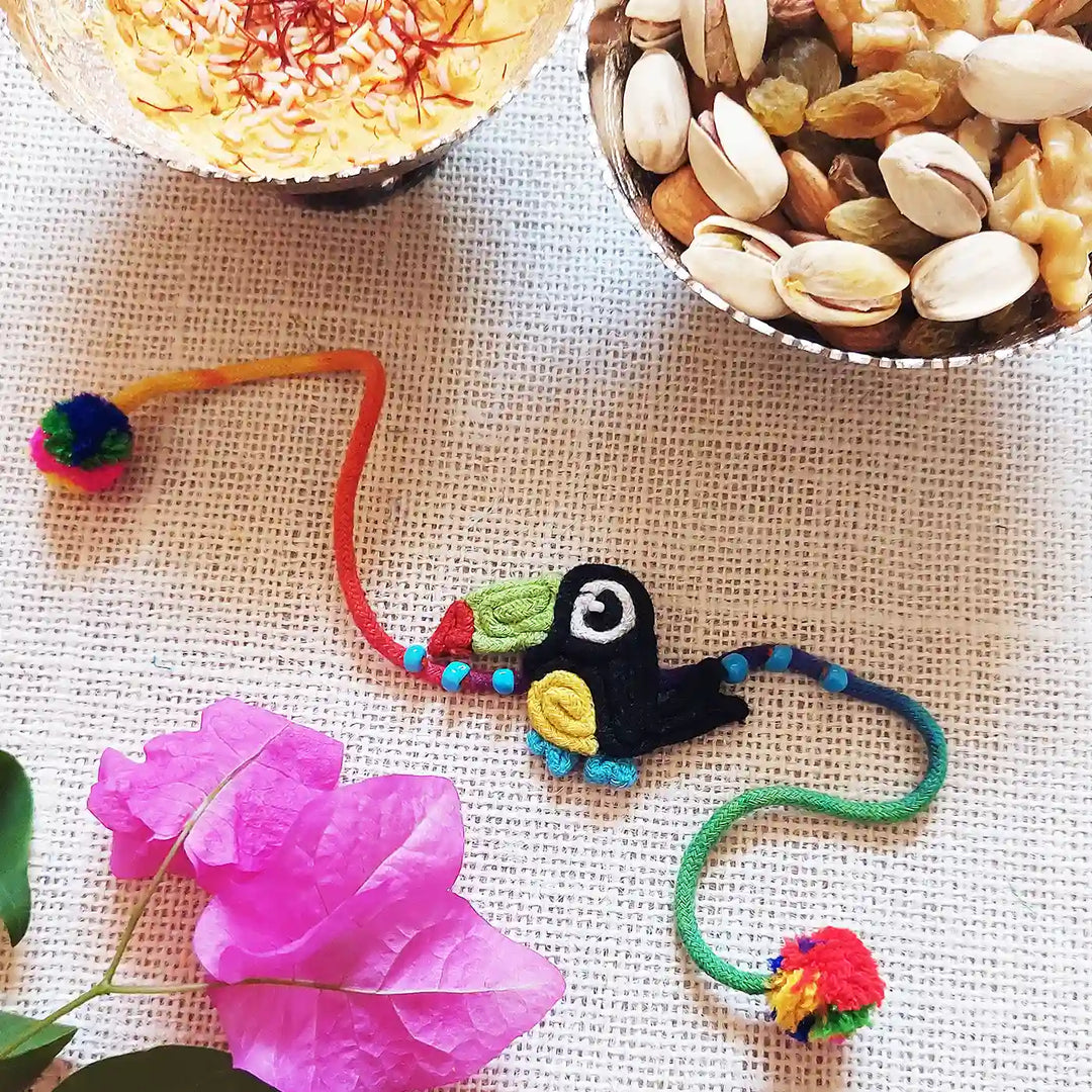 Handmade Dori Work Toucan Kids Rakhi With Roli Chawal - Styled Display with Snacks and Flowers