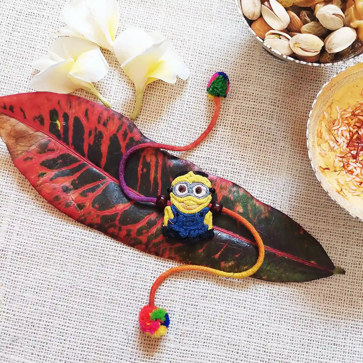 Handmade Dori Work The Minion Kids Rakhi With Roli Chawal - Styled on Leaf Decorative Setup