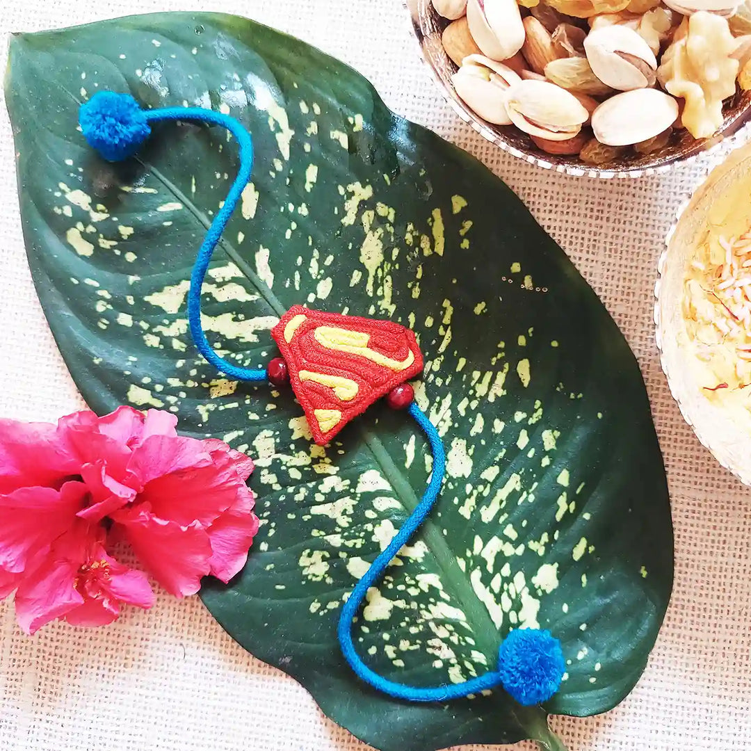 Handmade Dori Work Superman Kids Rakhi With Roli Chawal - Styled on Leaf with Props
