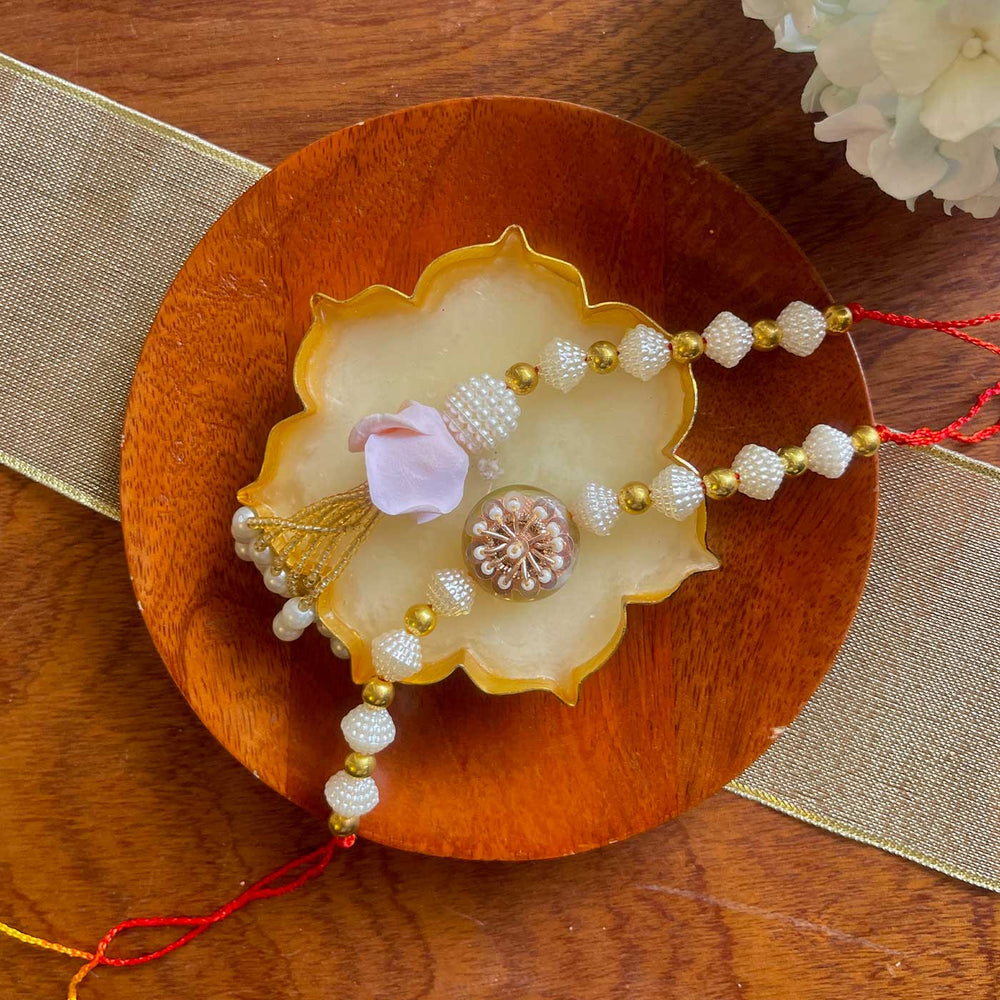 Handmade White And Gold Flower Design Pearl And Stone Bhaiya Bhabhi Rakhi - Full view on tray setting