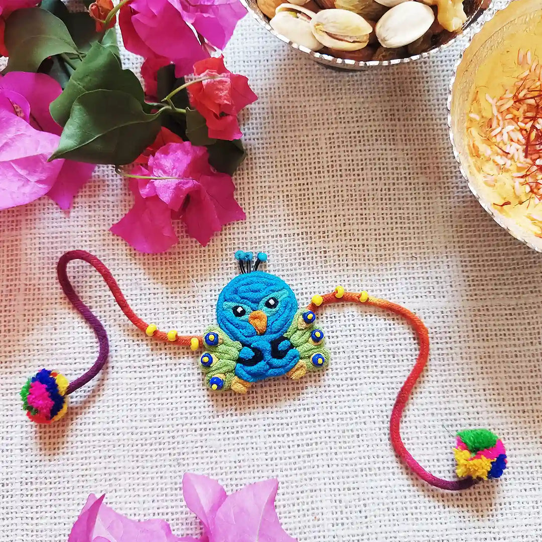 Handmade Dori Work Peacock Kids Rakhi With Roli Chawal - Styled Flat Lay with Decorations