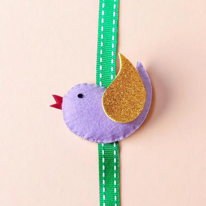 Handmade Bird Theme Felt Kids Rakhi With Roli Chawal - Front view of purple bird accessory