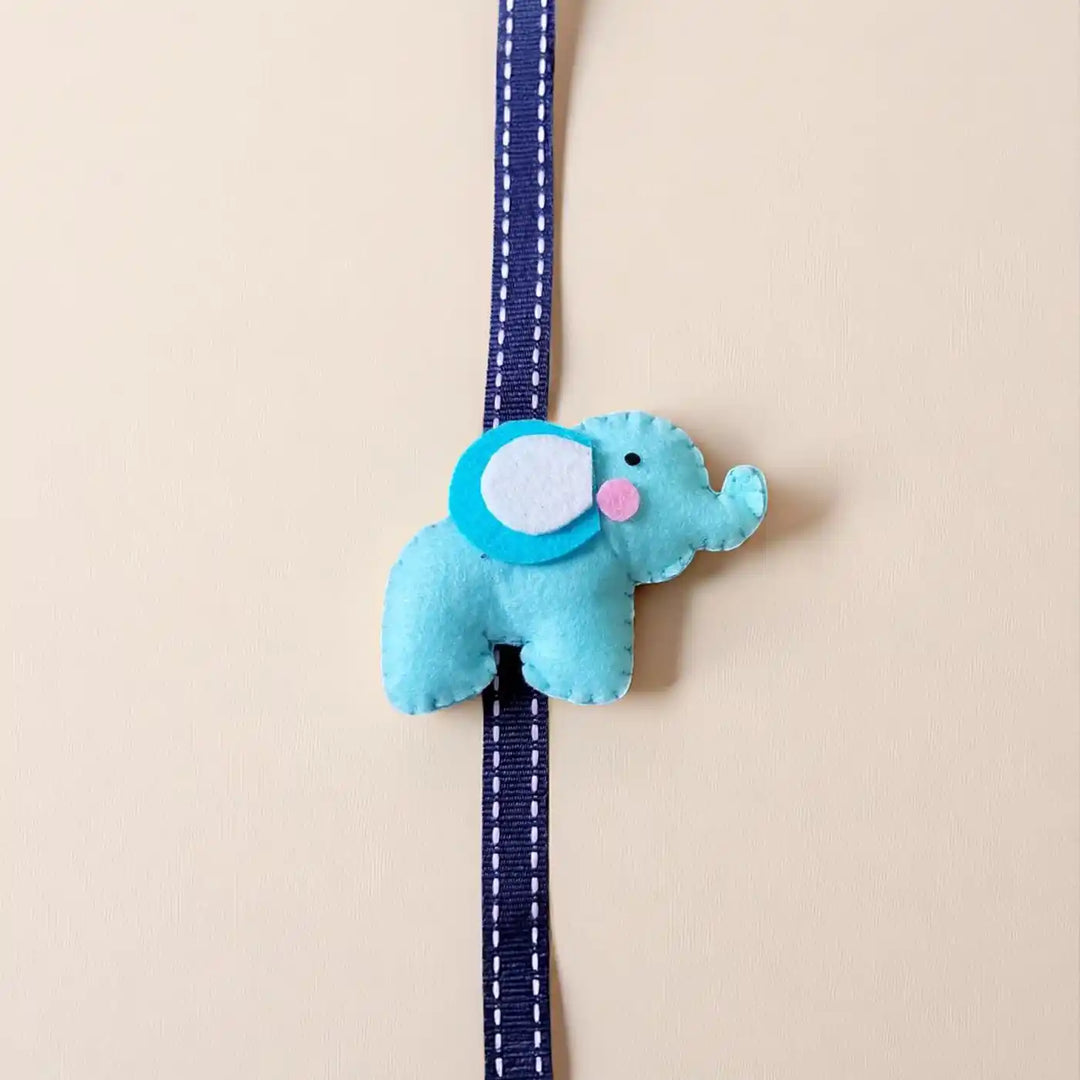 Handmade Elephant Theme Felt Kids Rakhi With Roli Chawal - Top View on Plain Background