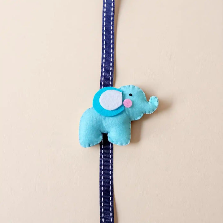 Handmade Elephant Theme Felt Kids Rakhi With Roli Chawal - Top View on Plain Background