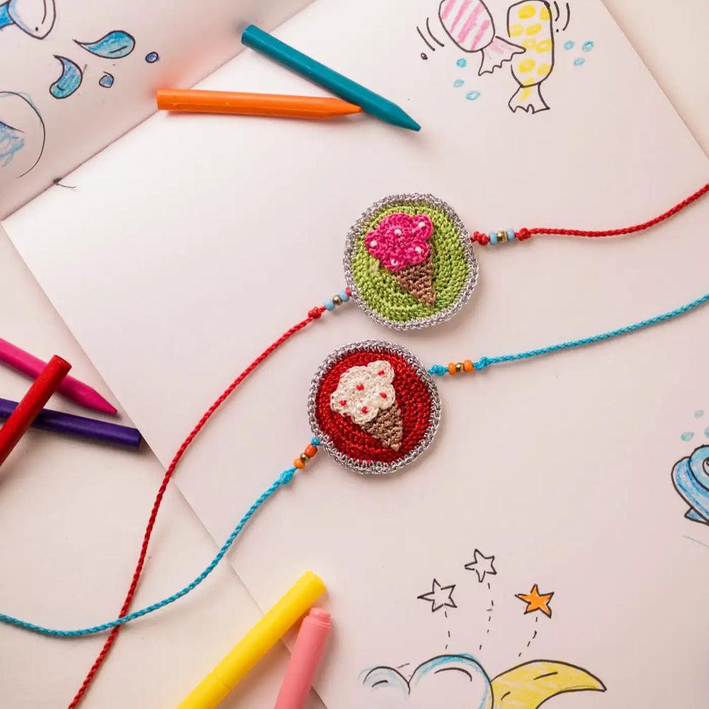 Handmade Crochet Ice Cream Theme Kids Rakhi With Roli Chawal Set Of 2 - Rakhi Bracelets Laid on Sketchbook
