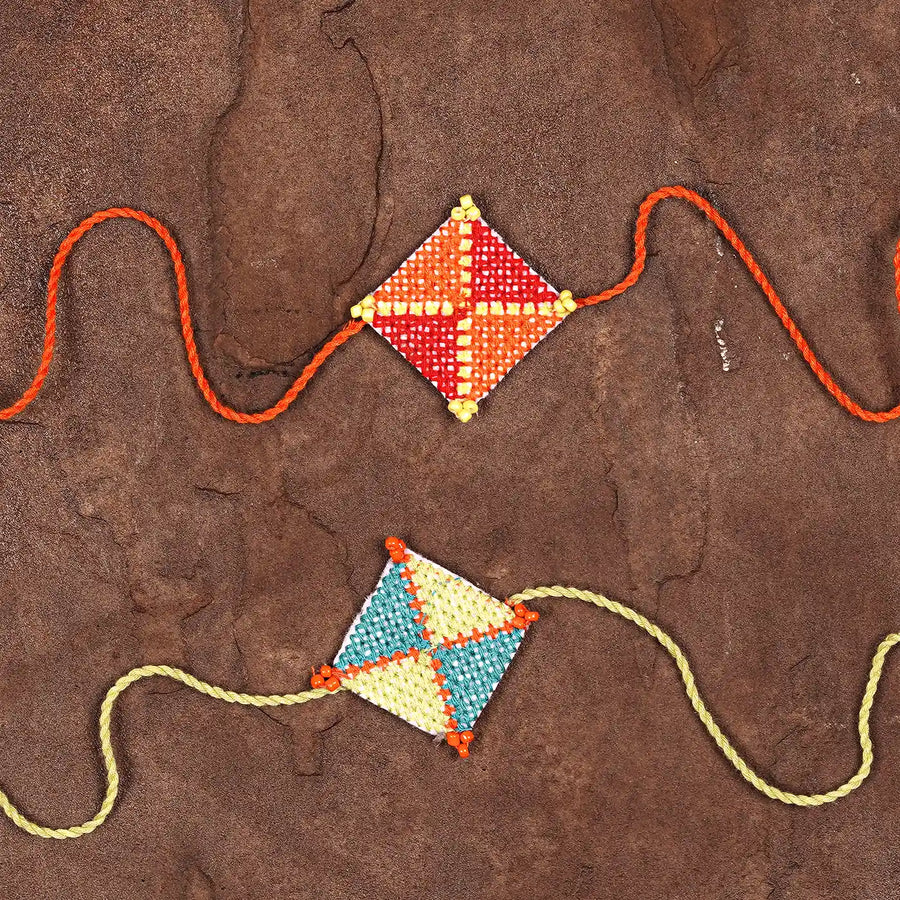 Hand Embroidered Cross Knot Rakhi With Roli Chawal Set Of 2 - Flat Lay Front View