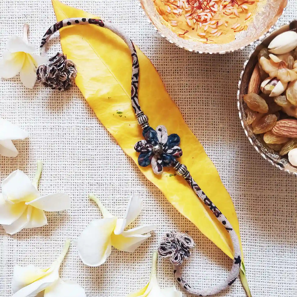 Handmade Dori Work Ajrakh Flower Rakhi With Roli Chawal - Styled Product with Props