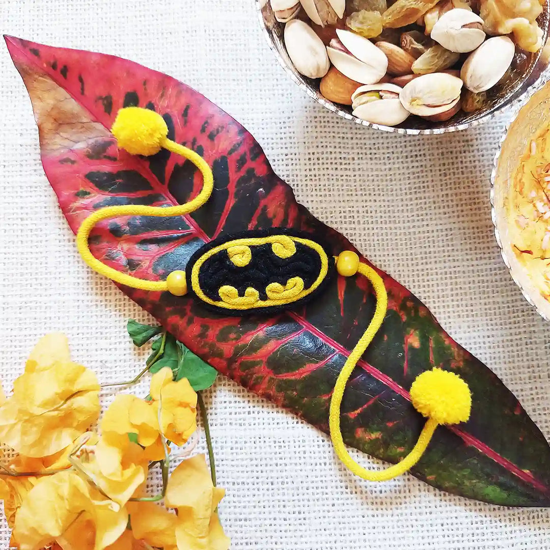 Handmade Dori Work Batman Kids Rakhi With Roli Chawal - Styled Product on Leaf and Snacks