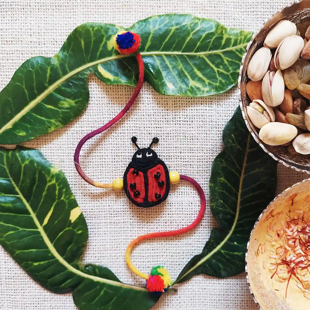 Handmade Dori Work Ladybird Kids Rakhi With Roli Chawal - Styled Flat Lay Presentation