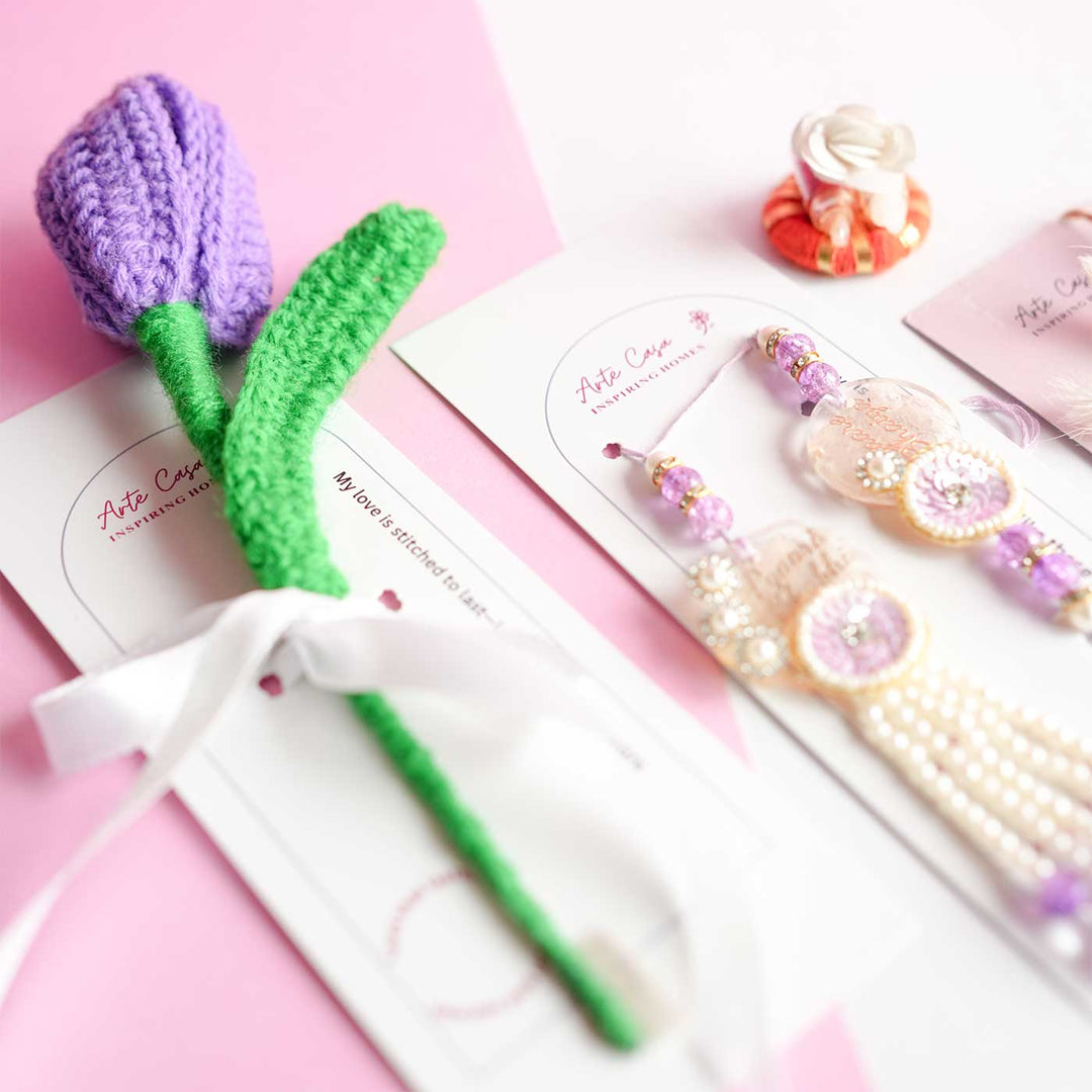 Personalized Handmade Crochet Tulip Dark Purple Rakhi Hamper Includes 1 Crochet Flower 1 Message Card And 2 Rakhis And Roli Chawal - Product Display with Accessories