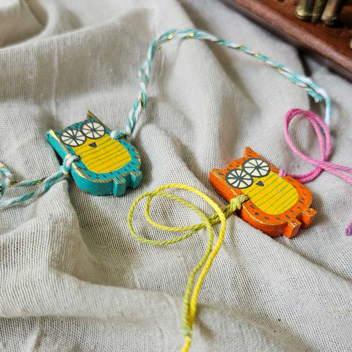 Handpainted Quirky Wooden Rakhi With Roli Chawal - Two Owl Bracelets on Fabric