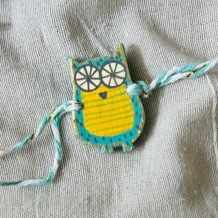 Handpainted Quirky Wooden Rakhi With Roli Chawal - Close-up of Blue Owl Bracelet