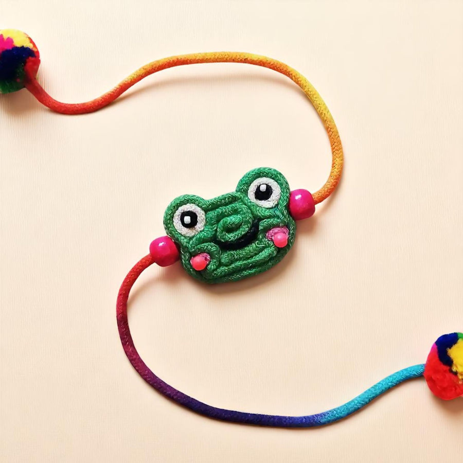 Handmade Dori Work Frog Kids Rakhi With Roli Chawal - Close-up on Plain Background