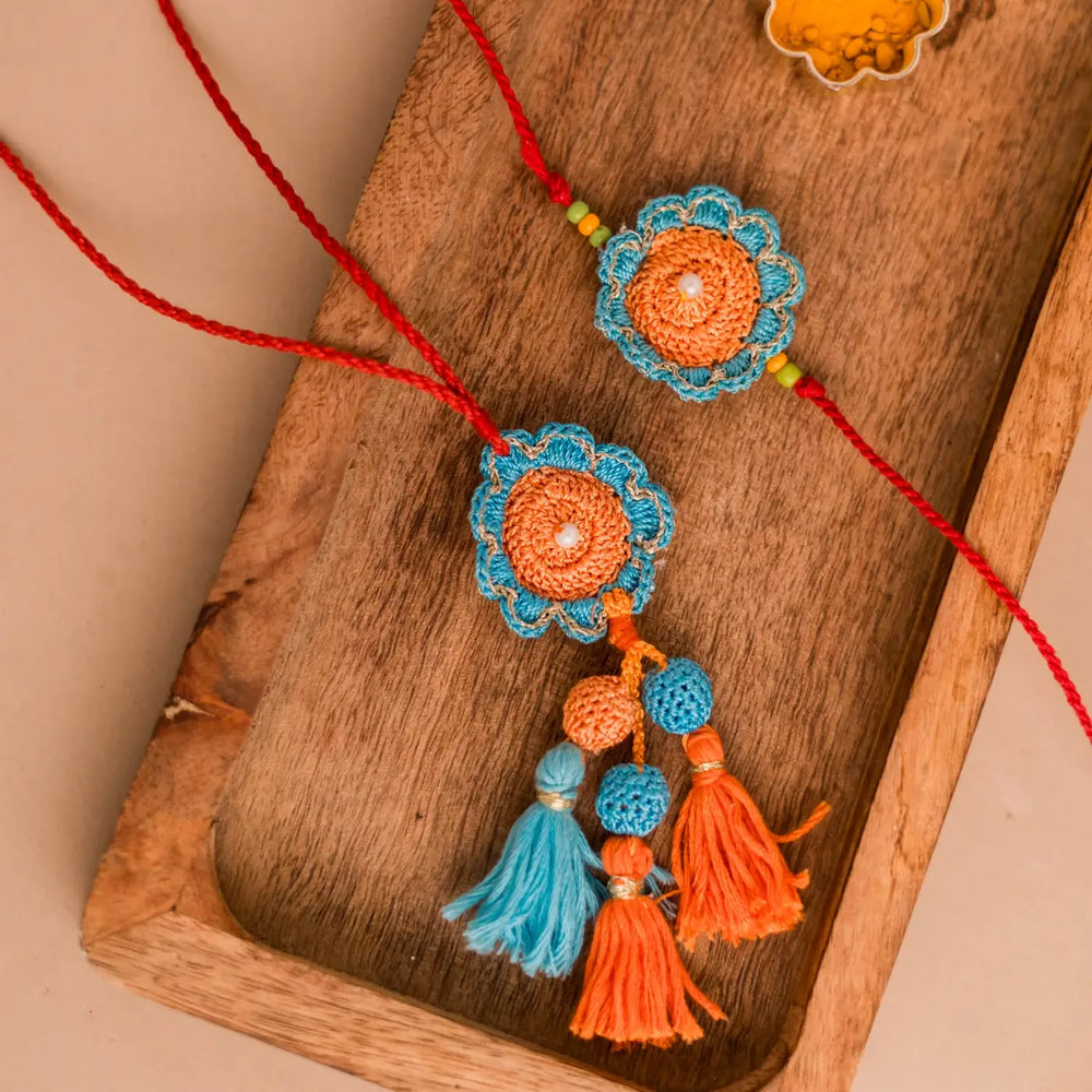 Handmade Crochet Blue And Orange Camelia Bhaiya Bhabhi Rakhi With Roli Chawal Set Of 2 - Close-up on Decorative Tassels
