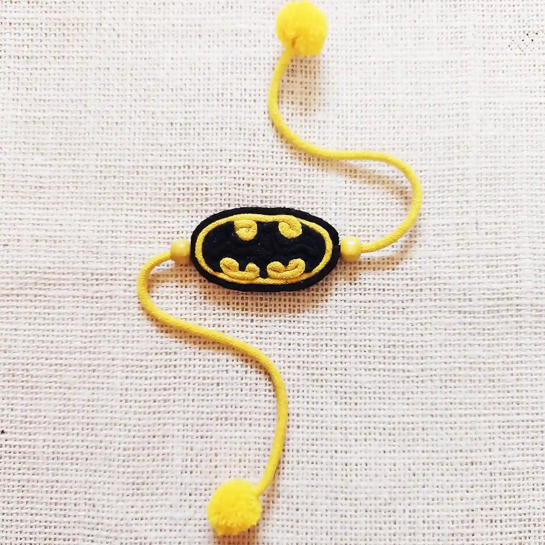Handmade Dori Work Batman Kids Rakhi With Roli Chawal - Flat Lay with Pompoms Visible