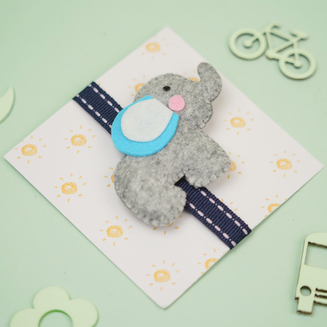 Handmade Elephant Theme Felt Kids Rakhi With Roli Chawal - Top Angle on Gray Elephant Ornament
