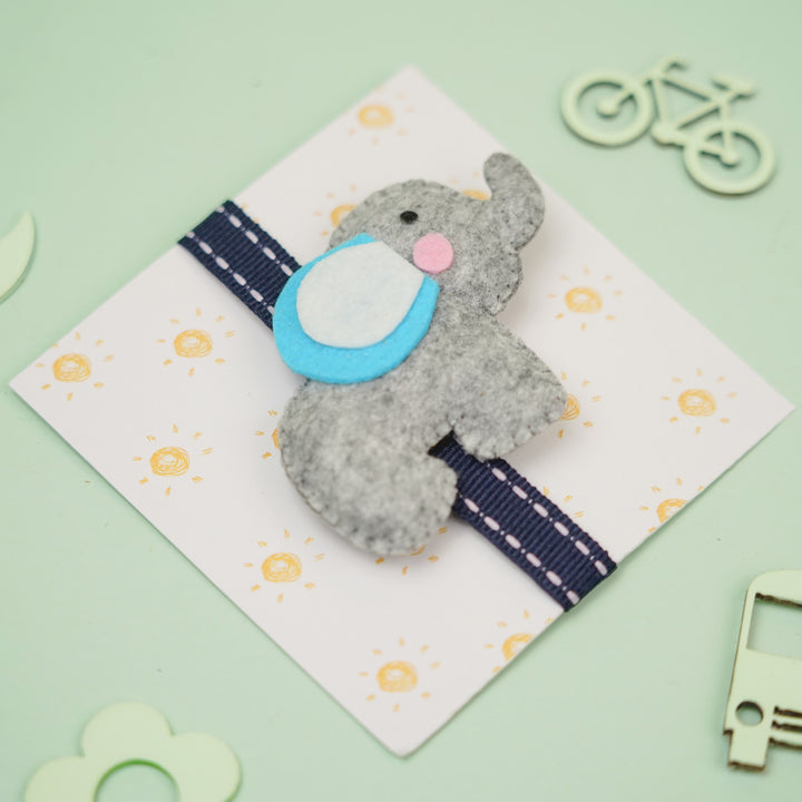 Handmade Elephant Theme Felt Kids Rakhi With Roli Chawal - Top Angle on Gray Elephant Ornament