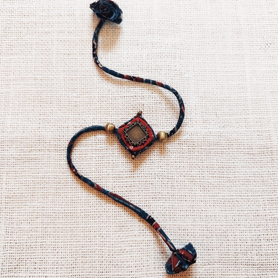 Handmade Dori Work Antique Ajrakh Rakhi With Roli Chawal - Front View on Fabric Background