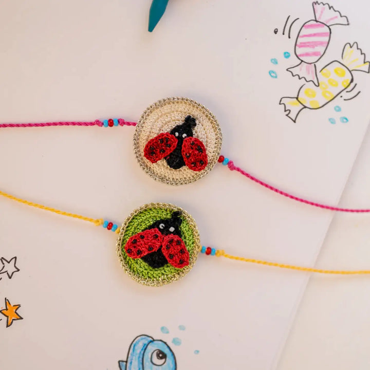 Handmade Crochet Beetle Theme Kids Rakhi With Roli Chawal Set Of 2 - Top-down paired bracelet display