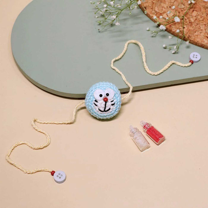 Handmade Crochet Doraemon Kids Lumba Rakhi With Roli Chawal - Laid flat with bead and buttons