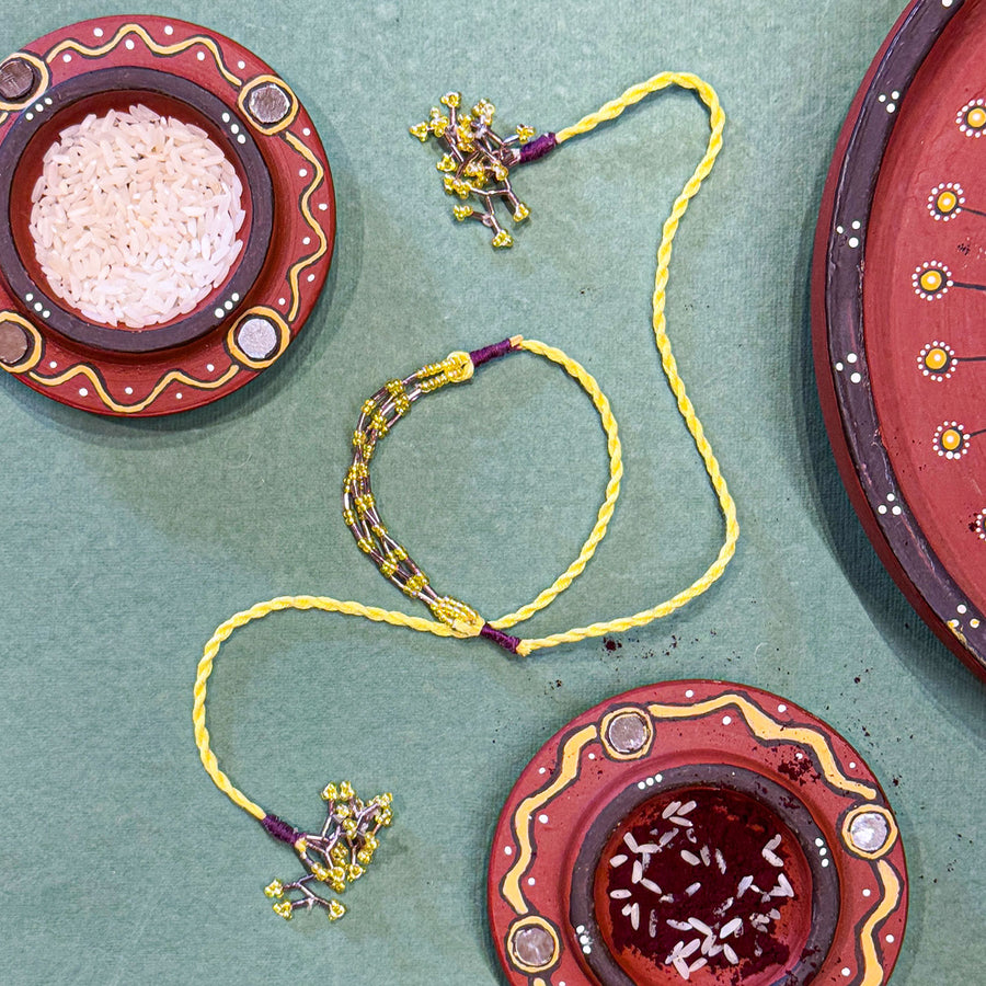 Handmade Reusable Yellow Corel And Jhumki Rakhi For Brother - Styled Flat Lay with Accessories