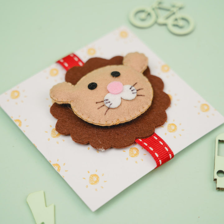 Handmade Lion Theme Felt Kids Rakhi With Roli Chawal - Close-up Angled View on Cardboard Backing
