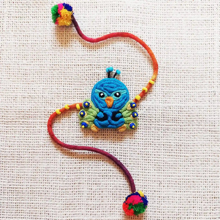 Handmade Dori Work Peacock Kids Rakhi With Roli Chawal - Flat Lay on Neutral Surface