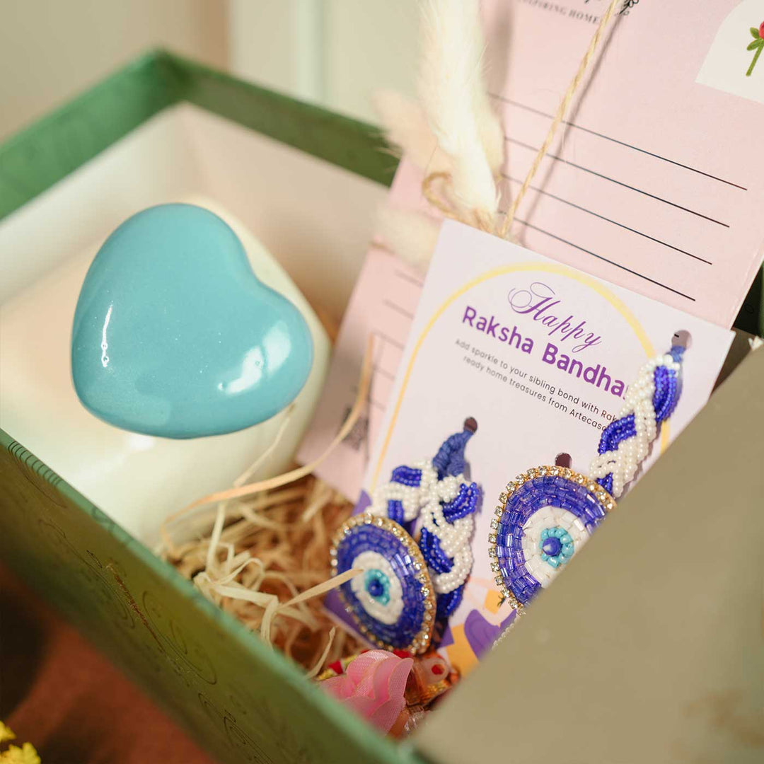 Personalized Handmade Chai Lover Theme Rakhi Hamper Includes 1 Gift Box 1 Mug 2 Rakhis 1 Roli Chawal 1 Candle And 1 Message Card - Close-up of Heart Mug and Card