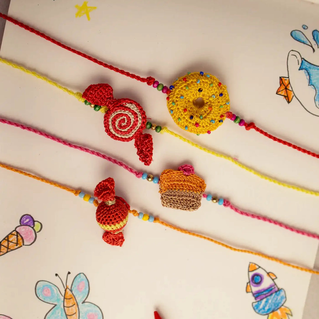 Handmade Crochet Candy Theme Rakhi With Roli Chawal Set Of 4 - Overhead View with Background Drawings