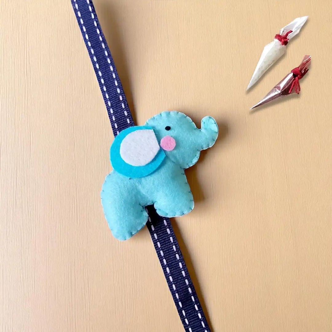 Handmade Elephant Theme Felt Kids Rakhi With Roli Chawal - Diagonal View on Blue Elephant Ornament