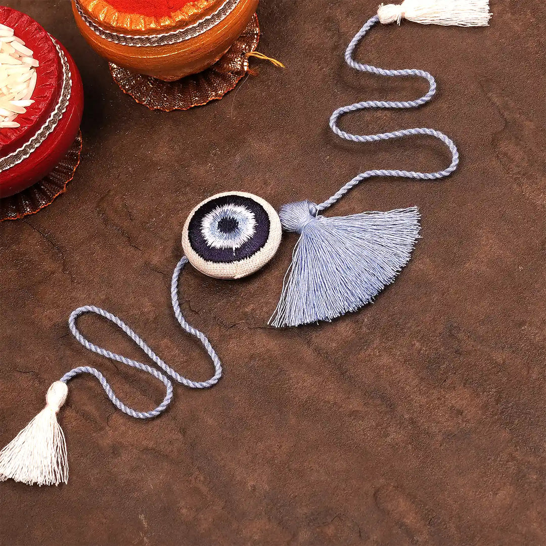 Hand Embroidered Evil Eye Rakhi With Roli Chawal - Styled product display with props