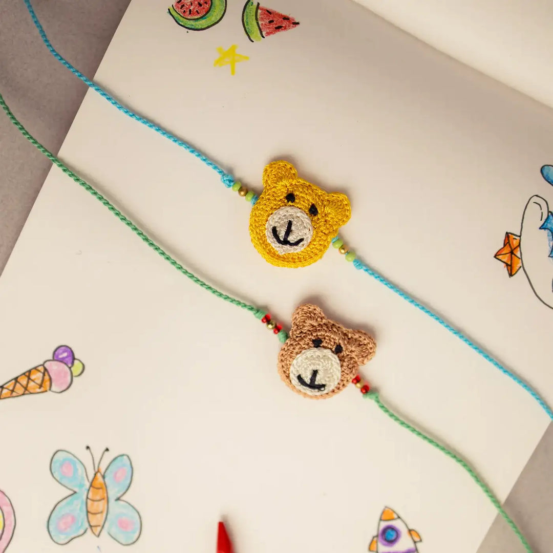 Handmade Crochet Bear Theme Kids Rakhi With Roli Chawal Set Of 2 - Close-up View on Illustrated Surface