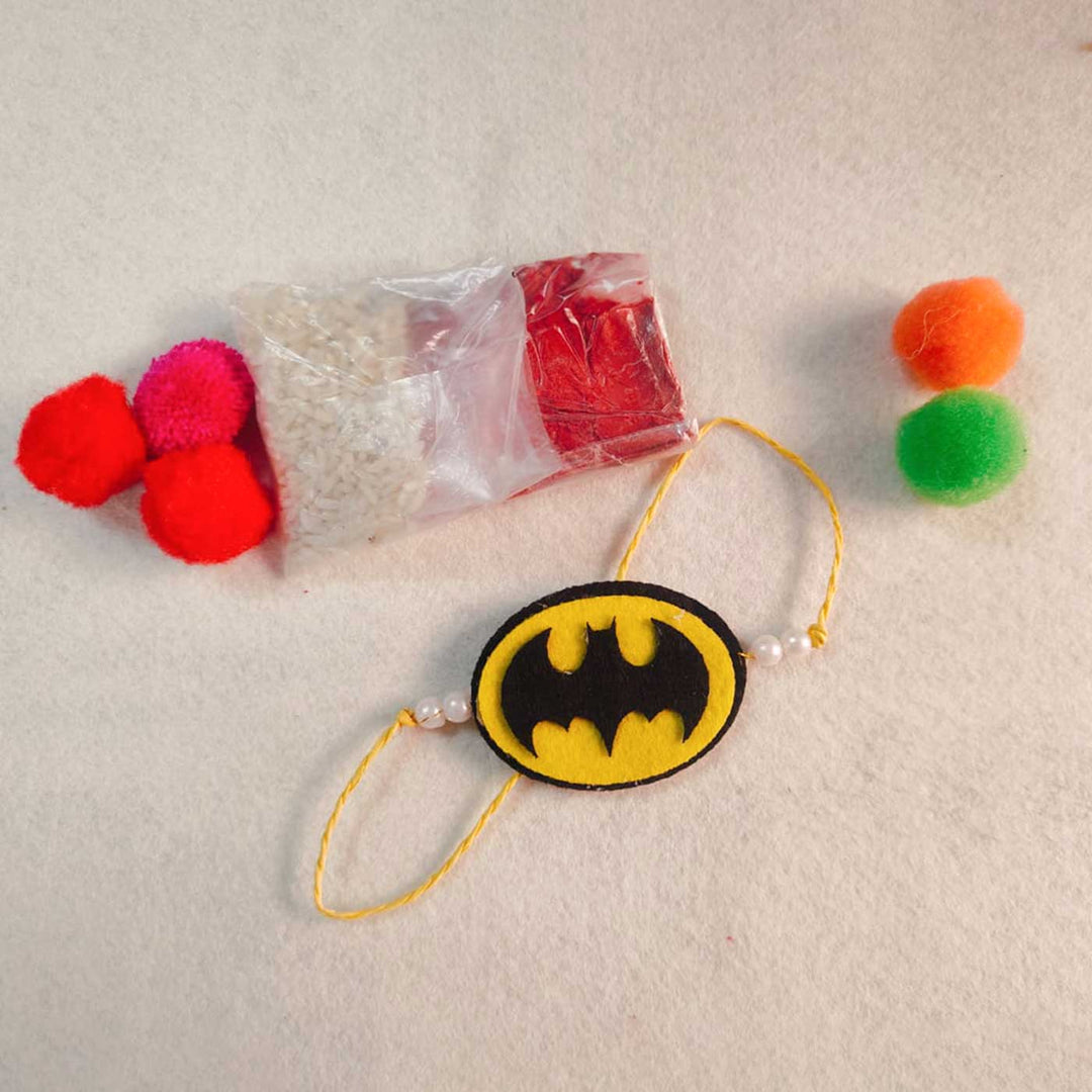 Handmade Beaded Batman Theme Pom Pom Felt Rakhi With Roli Chawal For Kids - Product with packaging elements
