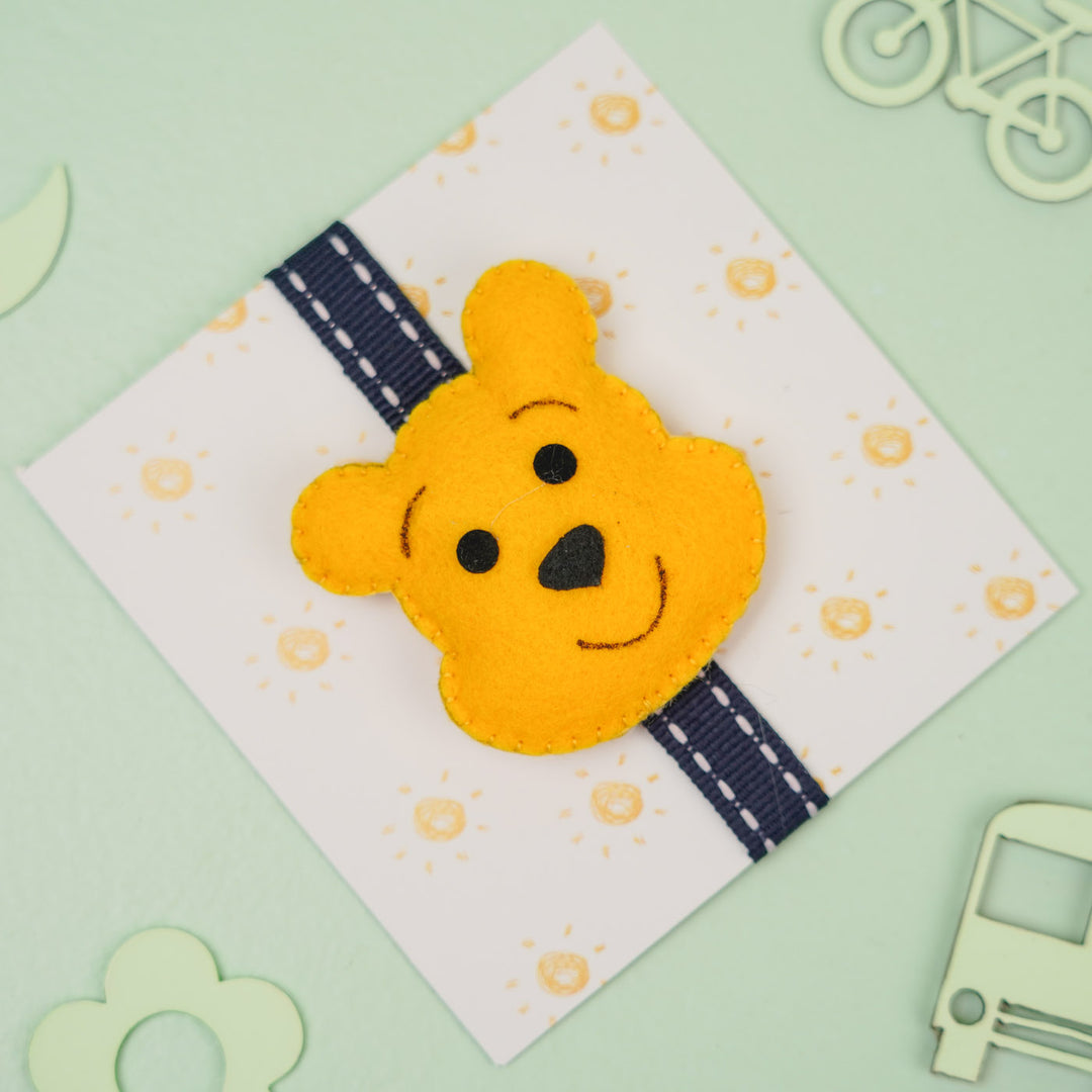 Handmade Pooh Theme Felt Kids Rakhi With Roli Chawal - Front View on Cardboard