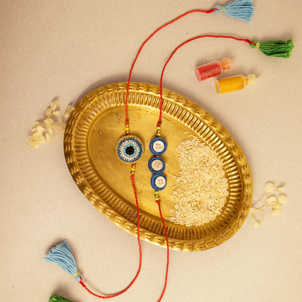 Handmade Crochet Noor And Nazar Evil Eye Rakhi With Roli Chawal Set Of 2 - Top view with decorative elements