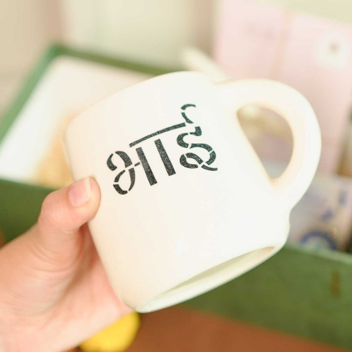 Personalized Handmade Love Theme Rakhi Hamper Includes 1 Gift Box 1 Mug 2 Rakhis 1 Roli Chawal 1 Candle And 1 Message Card - Mug Close-up Held in Hand