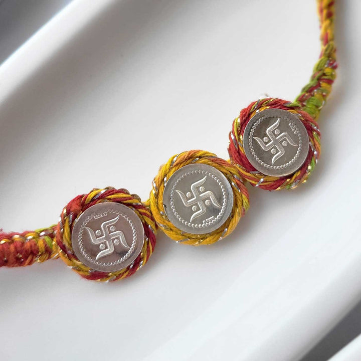 Handmade Three Swatik Coin Design Silver Rakhi Hamper With Roli Chawal For Brother - Close-up of decorative centerpiece