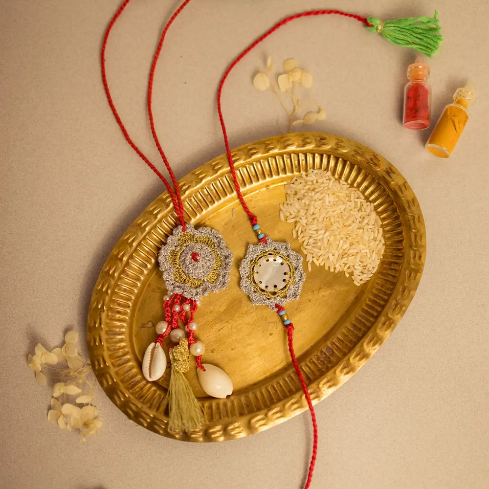 Handmade Crochet Sagar Seepi Bhaiya Bhabhi Rakhi With Roli Chawal Set Of 2 - Styled on platter with rice grains