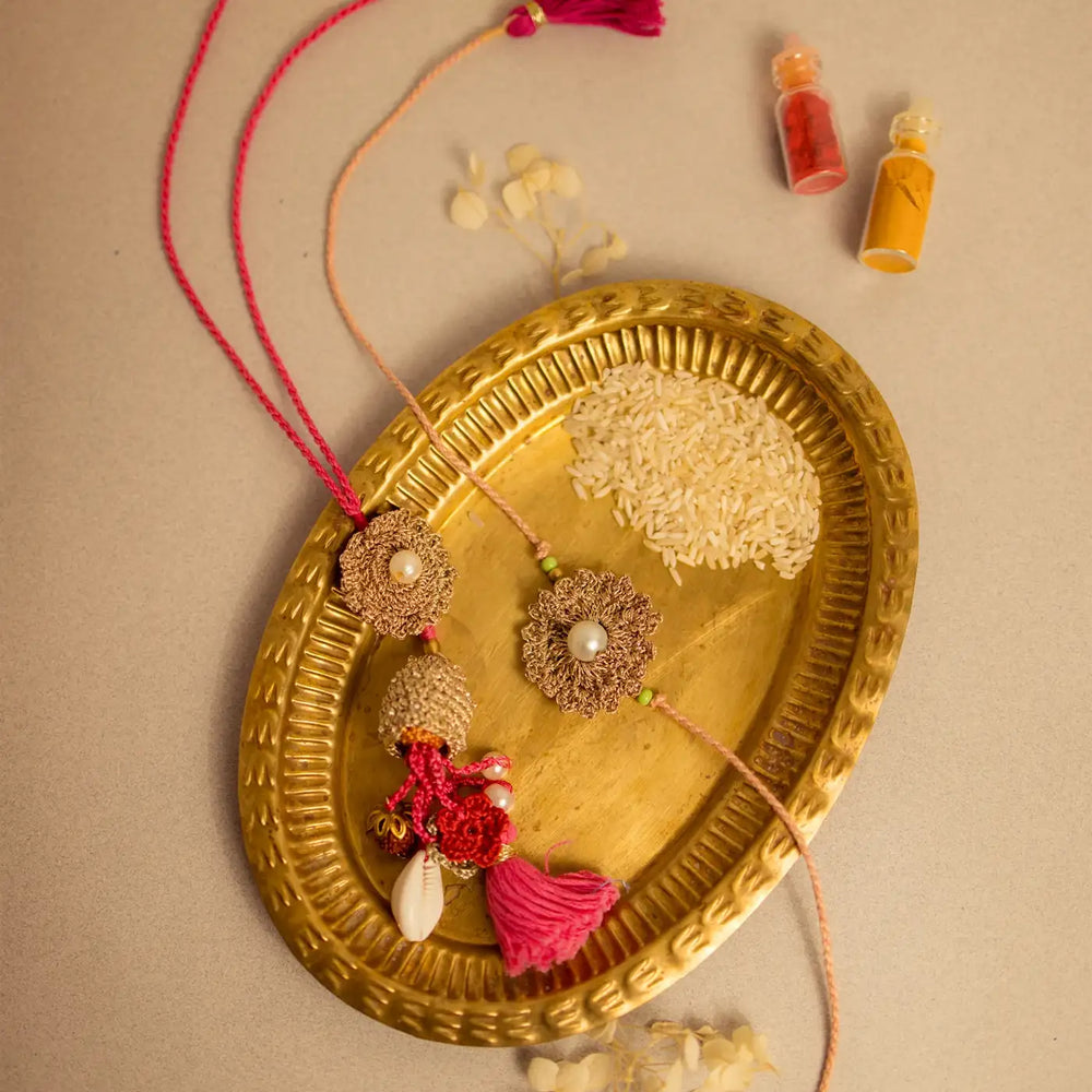 Handmade Crochet Moti Jhalar Bhaiya Bhabhi Rakhi With Roli Chawal Set Of 2 - Decorative tassels displayed on tray