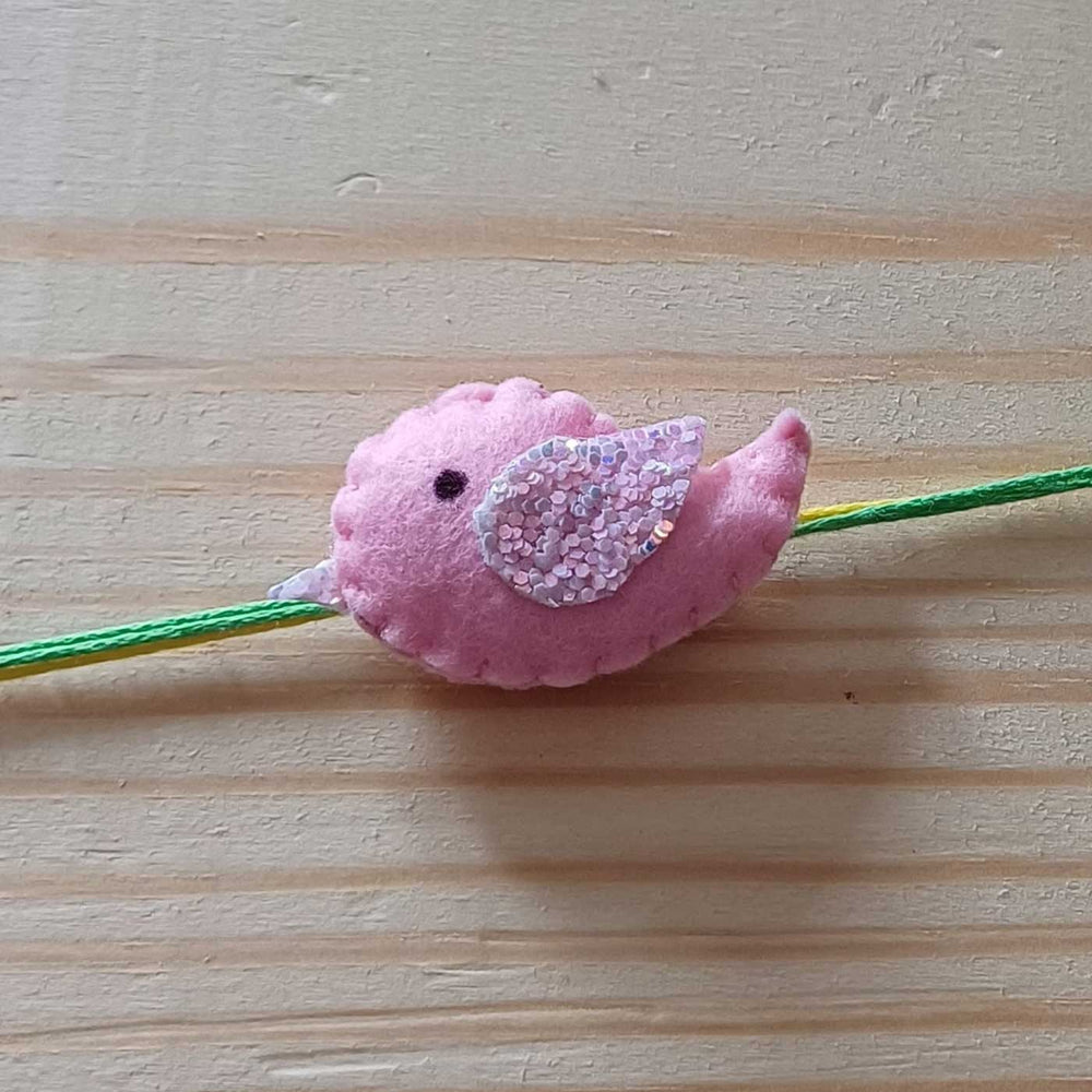 Handmade Pink Bird Theme Felt Kids Rakhi - Macro View on Wood Surface