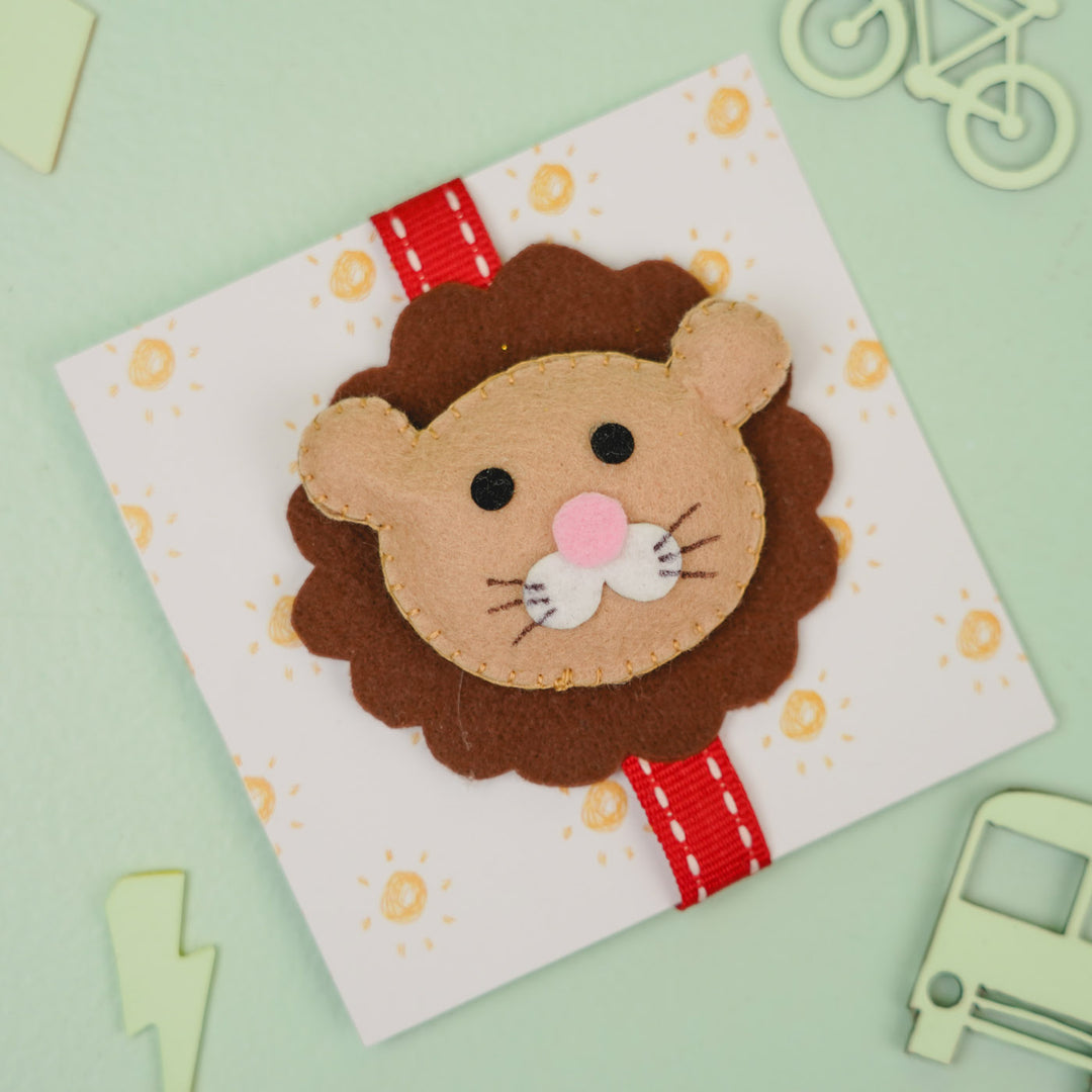 Handmade Lion Theme Felt Kids Rakhi With Roli Chawal - Angled Front View with Background Props