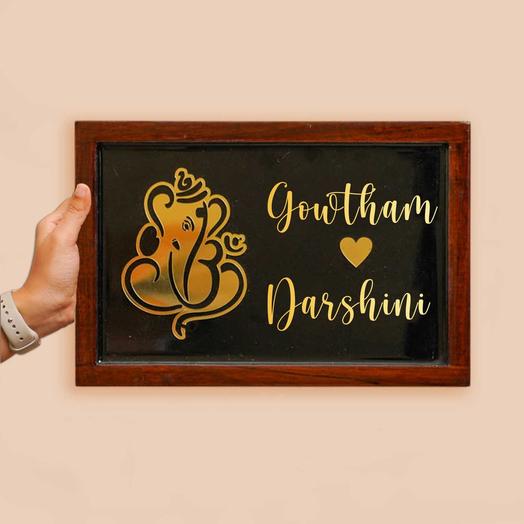 Personalized Ganesha Theme Resin Name Plate With Teak Wood Border For Couples - Front View with Hand Holding