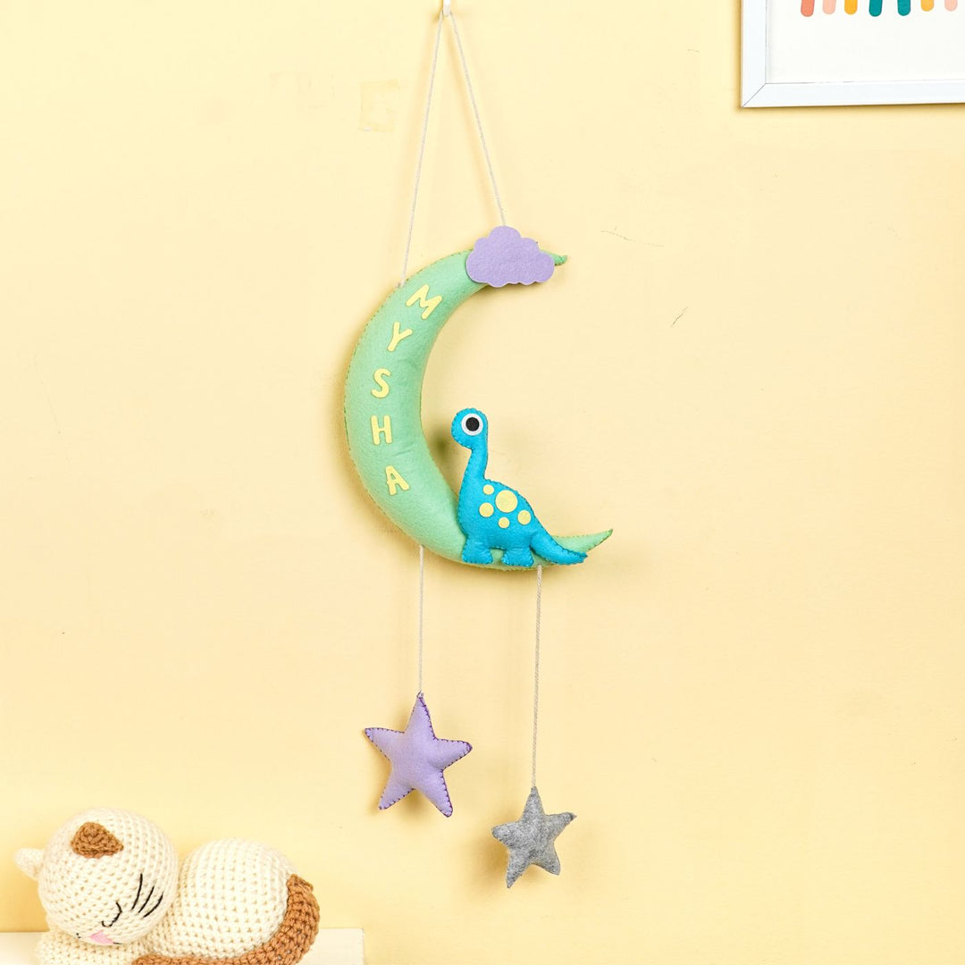 Handmade Dino On The Moon Kids Felt Name Hanging - Hanging against wall with toys nearby