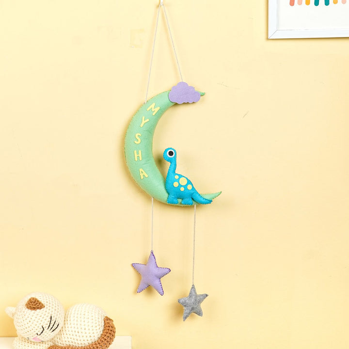 Handmade Dino On The Moon Kids Felt Name Hanging - Hanging against wall with toys nearby