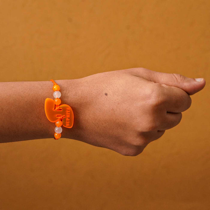 Personalized Handmade Alphabet Name Acrylic Rakhi With Roli Chawal - Orange Rakhi Worn on Wrist