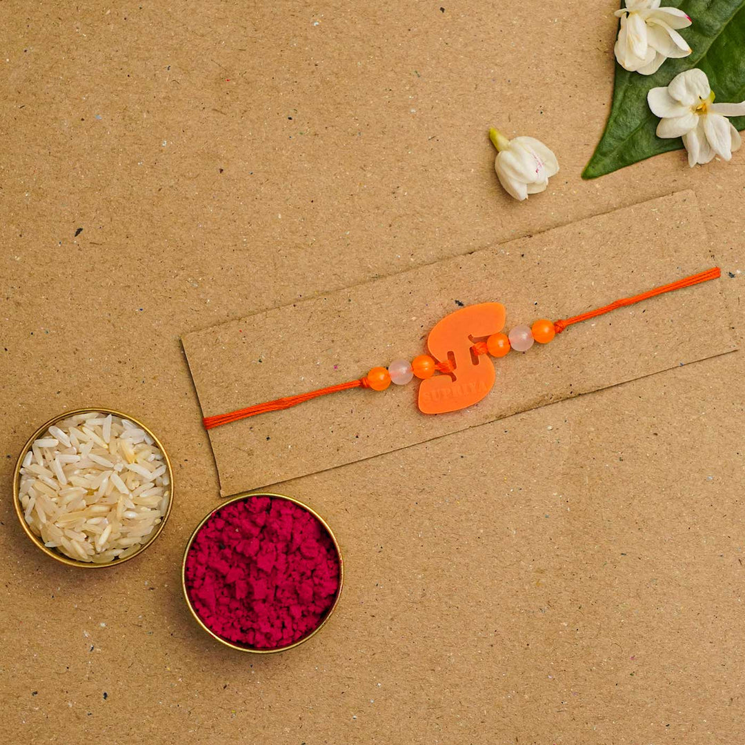 Personalized Handmade Alphabet Name Acrylic Rakhi With Roli Chawal - Orange Rakhi with Rice and Kumkum